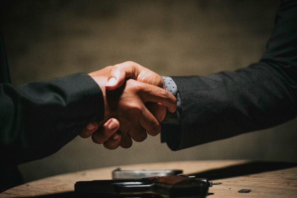 Two business professionals shaking hands over a wooden table